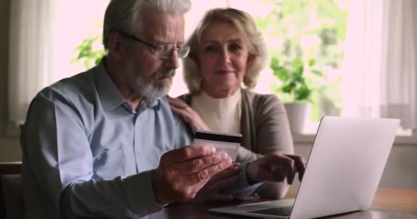 Idős pár, akik laptopot és hitelkártyát vásárolnak az interneten — Stock videók