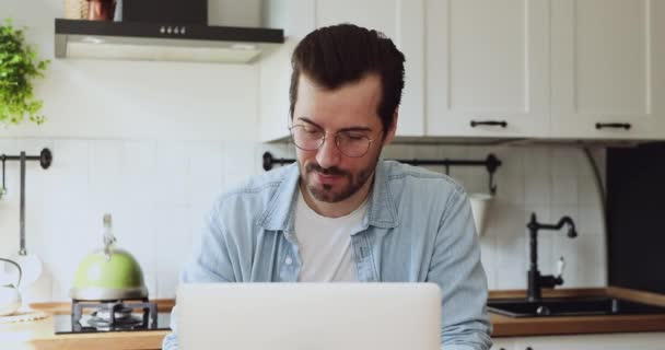 Jovem homem bonito feliz usando o computador na cozinha. — Vídeo de Stock