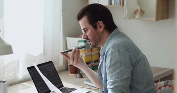 Lachende jonge mannelijke werknemer opnemen van audioboodschap op smartphone. — Stockvideo