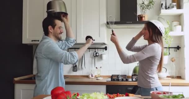 喜びに満ちた若い家族カップルがキッチンで戦いをプレイ. — ストック動画