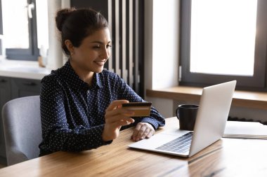 Gülümseyen Hintli kadın kredi kartıyla online alışveriş yapıyor.