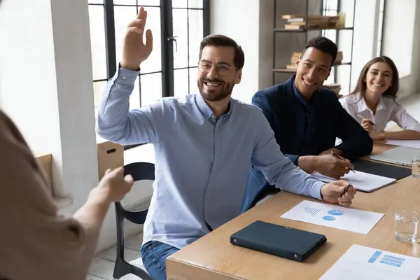 Smiling male employee raise hand at team meeting — Stock Photo, Image