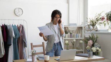 Genç bayan tasarımcı müşteriyle cep telefonunda konuşuyor.