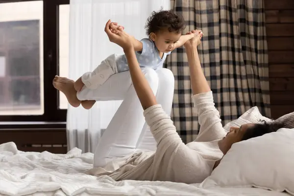 Loving biracial mother play in bed with toddler baby — Stok Foto