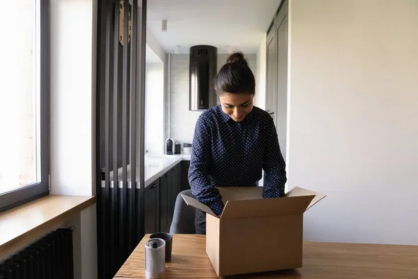Excited Indian woman unpack box with internet order