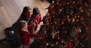 Anne ve çocuklar Noel ağacı süslüyorlar, yukarıdan manzara