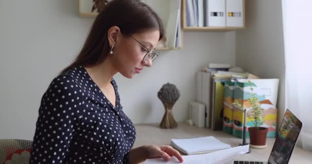 Gözlüklü, kağıt belgeler okuyan genç bir iş kadını.. — Stok video