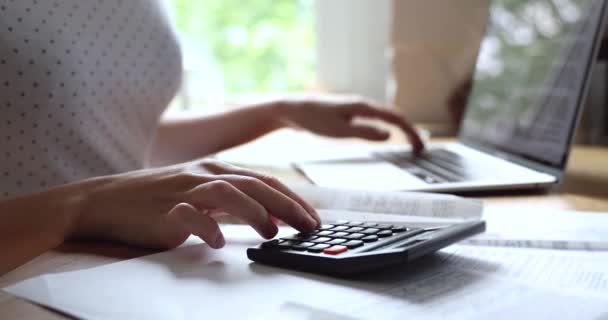 Primer plano mujer joven resumiendo los pagos con calculadora. — Vídeo de stock