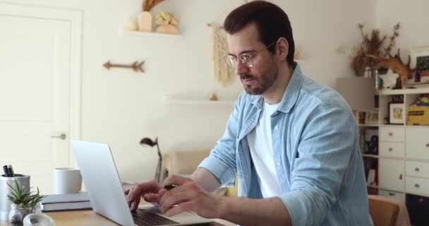 Fokussierter junger männlicher Unternehmer mit Brille, der am Computer arbeitet. — Stockvideo