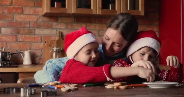 Η μαμά με τα παιδιά κάθονται στο τραπέζι στολισμένα χριστουγεννιάτικα κουλουράκια με μελόψωμο — Αρχείο Βίντεο