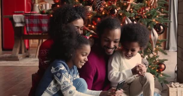 크리스마스 장식가 옥에서 스마트폰으로 즐거운 시간을 보내고 있는 아프리카 가족 — 비디오