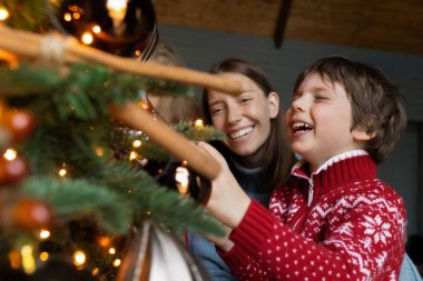 Mutlu anne ve küçük oğlu Noel ağacını evde süslüyor.