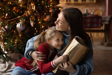 Mutlu anne ve küçük kızı Noel hediyelerini birlikte açıyor.