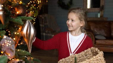 Mutlu küçük kızın geniş pankartı Noel ağacını süslüyor.