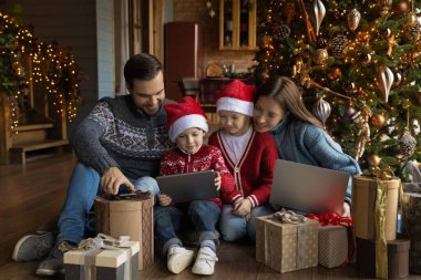 Çocuklarla gülümseyen aile tabletten video izliyor.