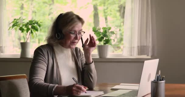 Бабушка носить гарнитуру с помощью ноутбука получить виртуальную консультацию по видеокассету — стоковое видео