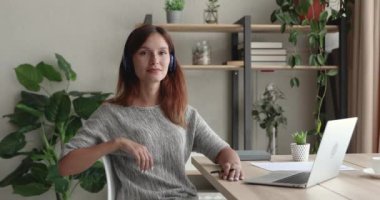 Gülümseyen, 30 'lu yaşlarda, kızıl saçlı, kulaklıklı bir kadının portresi..