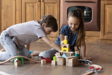 Mutlu küçük çocuklar evlerinde ahşap demiryollarıyla oynarlar.