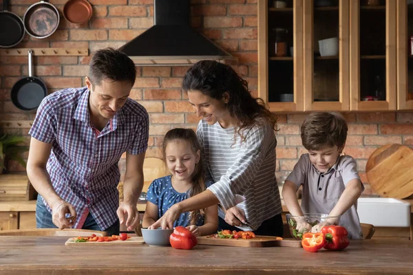 Šťastná rodina s dětmi vaření salát v kuchyni — Stock fotografie