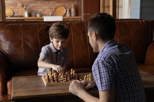 Rapaz esperto jogar xadrez com o pai — Fotografia de Stock