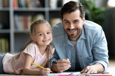 Genç yakışıklı baba kızıyla resim çiziyor..