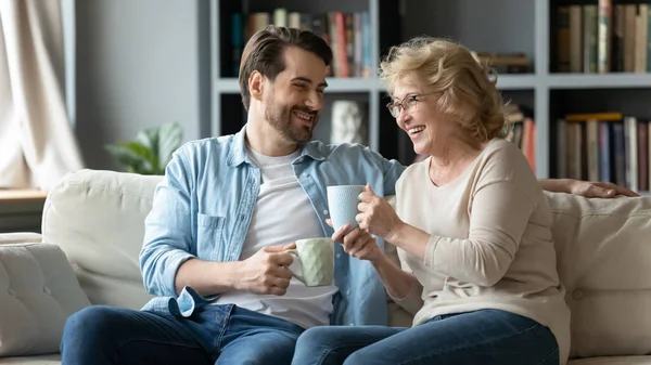 Lycklig man berättar rolig historia för skrattande medelålders mamma. — Stockfoto