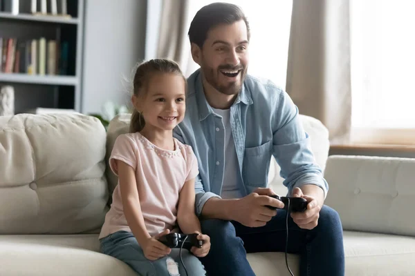 Souriant jeune père jouer à des jeux vidéo avec sa fille. — Photo