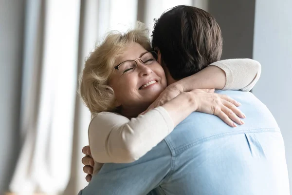 Carinhoso jovem visitando madura mamãe aposentada. — Fotografia de Stock