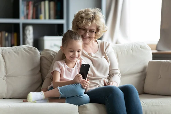 Sorrindo diferentes gerações femininas família jogando jogos para celular. — Fotografia de Stock