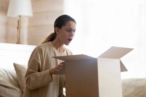 Annoyed millennial woman customer of internet shop receiving broken goods — Stock Photo, Image