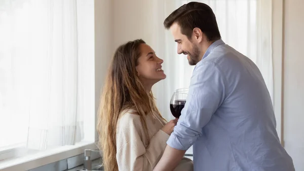 Hartstochtelijk liefhebbend paar knuffelen bij keuken holding bril van wijn — Stockfoto