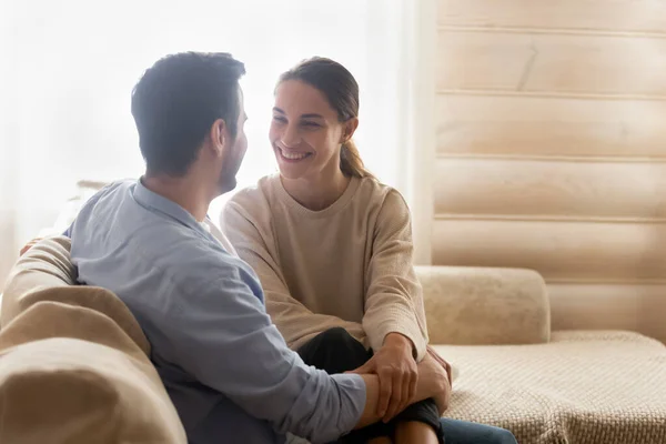Happy loving millennial couple embracing while sitting on sofa — Stock Photo, Image