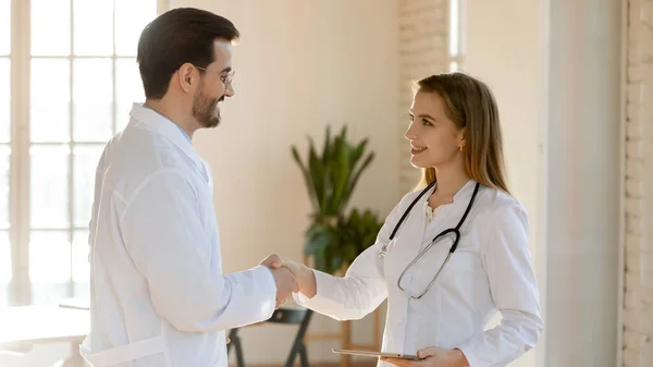 Joven terapeuta dando la bienvenida a su nuevo compañero de equipo en la clínica —  Fotos de Stock