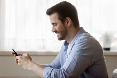 Mutlu gülümseyen genç adam akıllı telefondan arıyor.