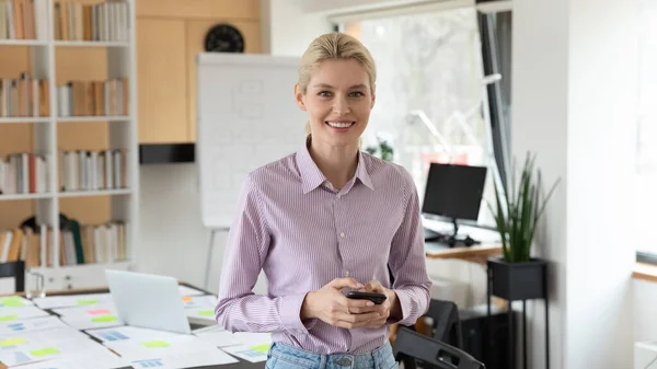 Porträt einer lächelnden jungen europäischen Geschäftsfrau mit Handy in der Hand. — Stockfoto