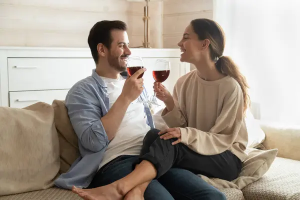 Famiglia millenaria seduta sul divano con bicchieri di vino che celebrano l'anniversario — Foto Stock