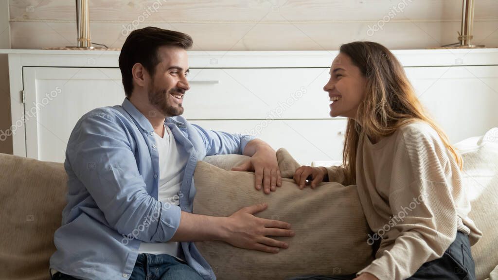 Pleasant millennial family couple having cheerful conversation at living room