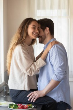 Mutfakta kucaklaşan sevecen aşıklar sebze salatası yapmaktan çekiniyorlar.