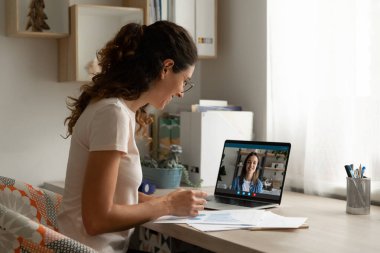 İş arkadaşıyla proje istatistikleri üzerinde çalışan gülümseyen kadın, internette sohbet ediyor.