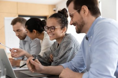 Ofiste bilgisayarlar üzerinde çalışan mutlu, çok kültürlü meslektaşlar..