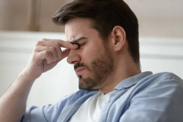 Varón cansado frotando puente de nariz sufriendo de dolor en los ojos —  Fotos de Stock