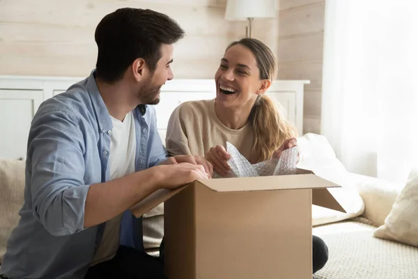 Alegre riendo millennial marido y esposa unboxing paquetes después de la reubicación — Foto de Stock