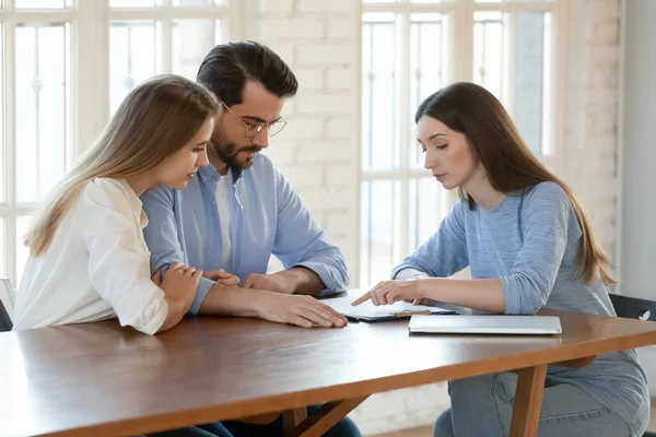 Young woman lawyer explaining agreement details to focused millennial spouses — Stock Photo, Image