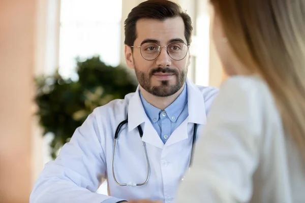 Přátelsky pozorný mužský lékař naslouchající stížnostem pacientky — Stock fotografie