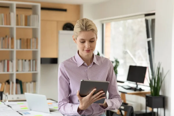 Aangename glimlachende jonge zakenvrouw met behulp van computer tablet. — Stockfoto