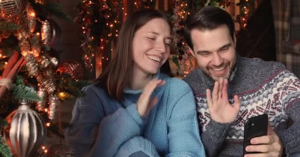 Cheery couple talking to family congratulates Merry Christmas by videocall — ストック動画