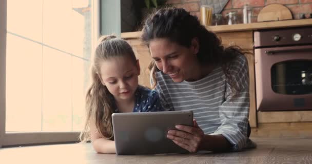 Malá dcera a matka pomocí tabletu mluvit ležící na podlaze — Stock video