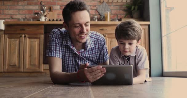 Pai e filho passam o tempo juntos se divertindo usando tablet — Vídeo de Stock