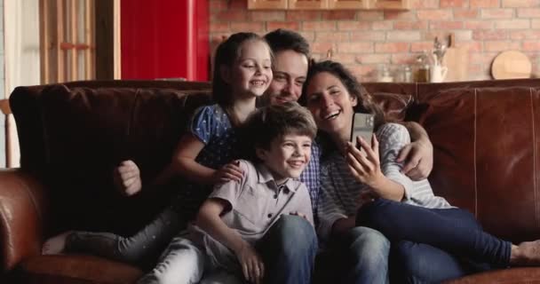 Familjer med barn sitter på soffan och har roligt med mobilen — Stockvideo