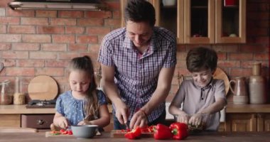 Baba ve küçük çocuklar evde salata hazırlıyorlar.